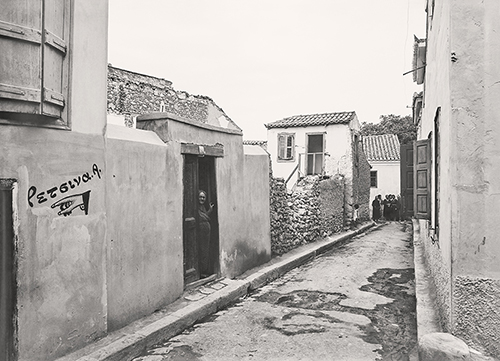 Black and white photo of Ptolemaiou Street in September 1932.  There is a group of women standing at the far end of the street near the Church of Vlassarou